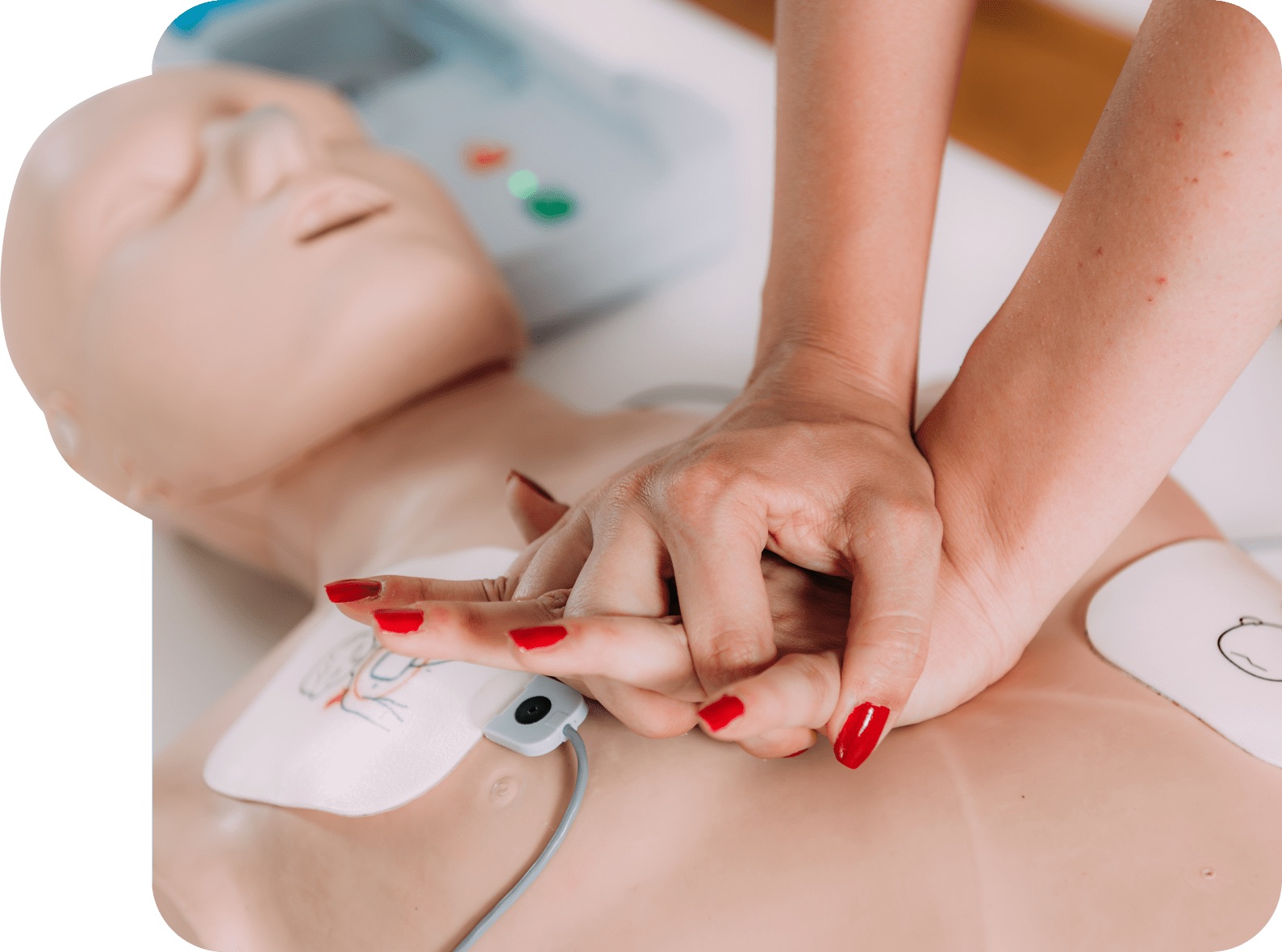 Gros plan sur une personne pratiquant la réanimation cardio-respiratoire (RCR) sur un mannequin, avec l'utilisation de patchs de défibrillation. Cette image illustre la partie pratique d'une formation RCR hybride, combinant apprentissage en ligne et exercices en présentiel.